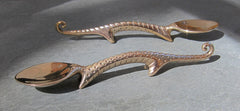 a 4 inch long polished bronze dinosaur shaped baby spoon