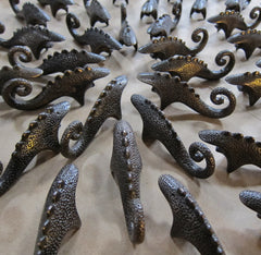 a dozen dark bronze dinosaur shaped bottle openers with spiral tails