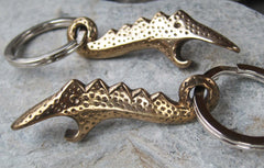 a 2 1/2" long polished bronze dinosaur inspired key chain bottle opener