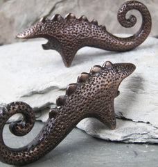a dark bronze dinosaur inspired bottle opener with a spiral tail